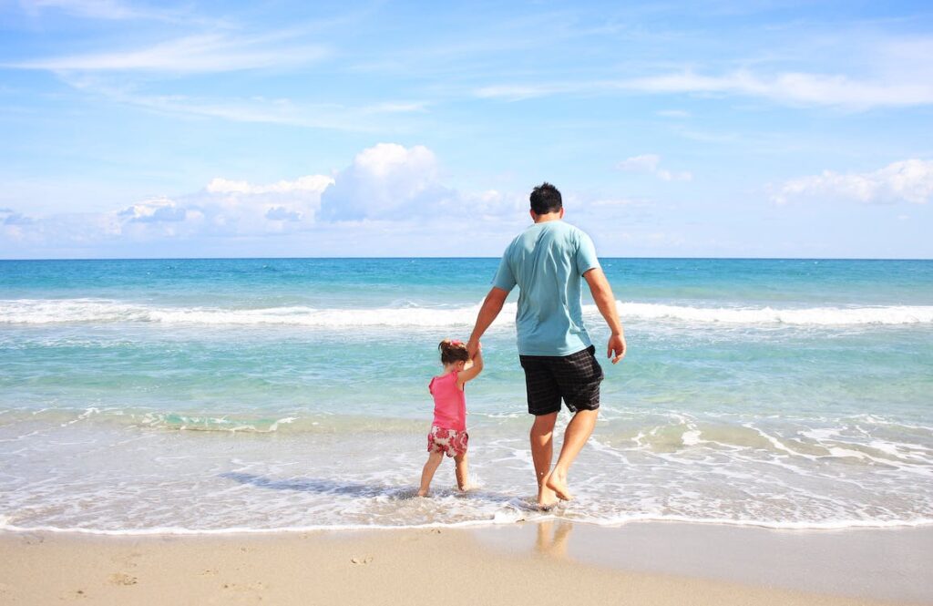 砂浜で手をつなぐ父親と娘の写真