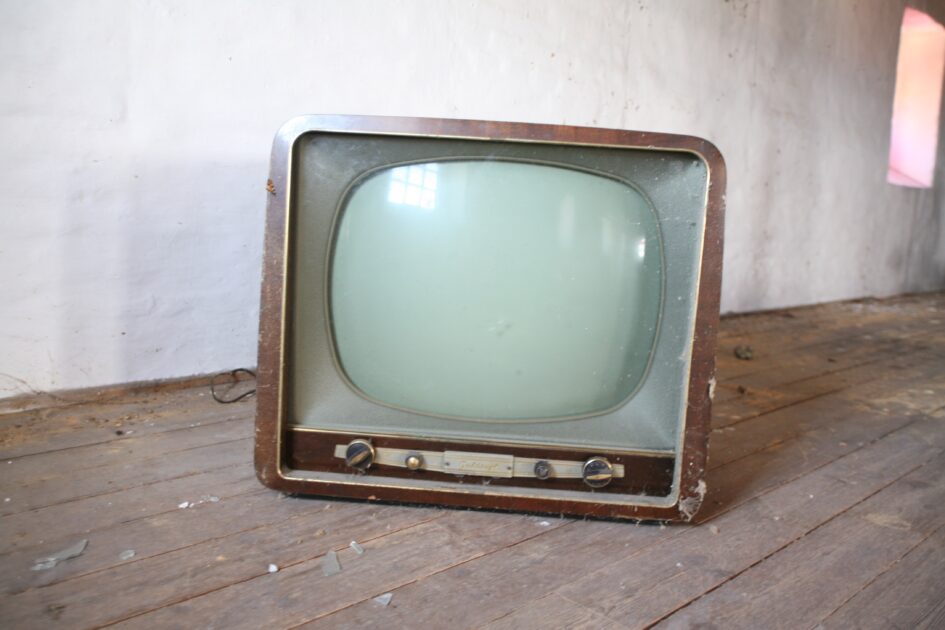 古い型式のテレビが汚れた床に置かれている写真